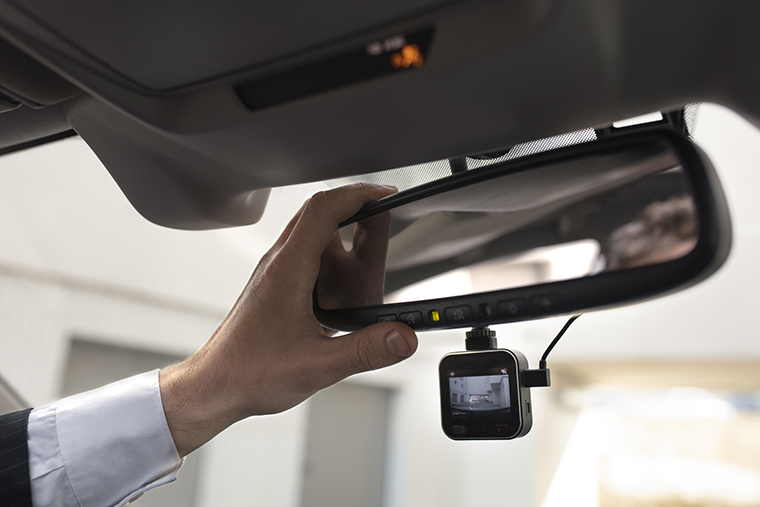 A man adjusts the rearview mirror with a video recorder